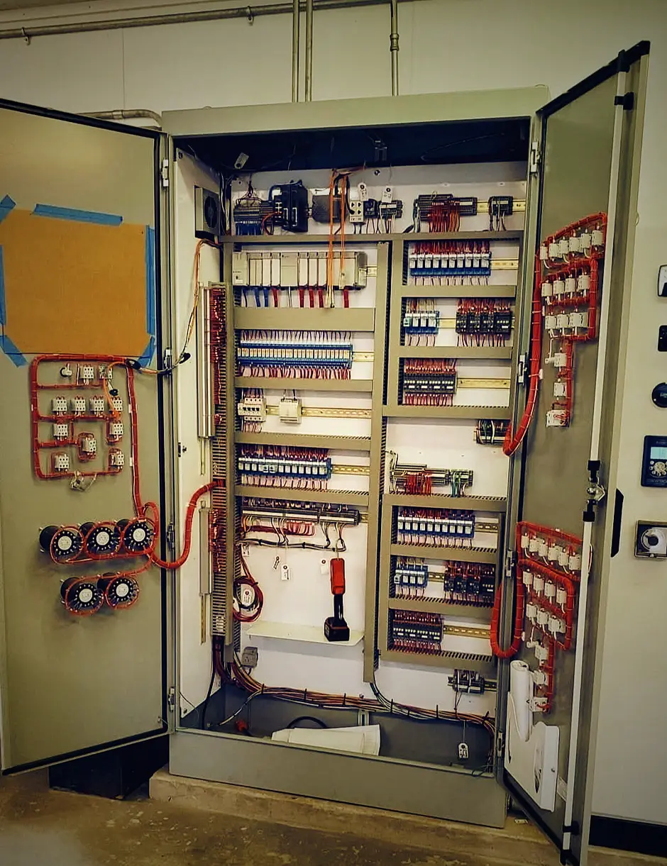 A full control cabinet built and wired by Ogun Factory Automation, both doors open: combed control wiring on DIN rails, a PLC rack, terminal blocks, relays, and an operator panel